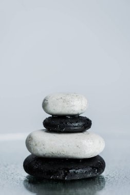 White and black zen stones on wet glass isolated on grey  clipart
