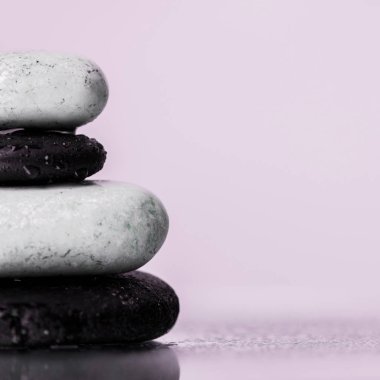 Close up view of wet zen stones on glass with water drops isolated on purple  clipart