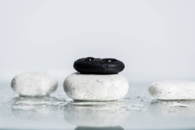 Back and white zen stones with water drops on wet glass on grey background clipart