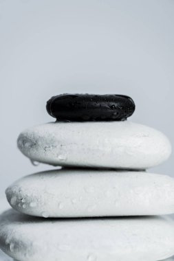 Su damlalarındaki siyah ve beyaz zen taşlarından oluşan makro çekim gri üzerine izole edilmiş.