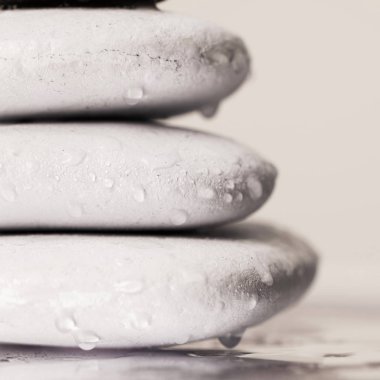 Makro beyaz zen taşları, ıslak camların üzerine su damlaları, bej rengi izole edilmiş.
