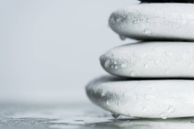 Sudaki beyaz zen taşlarının makro görüntüsü gri camların üzerine düşer.