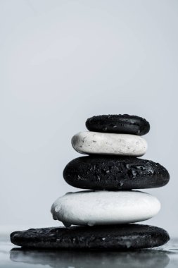 Close up view of stacked black and white zen stones on wet glass isolated on grey clipart