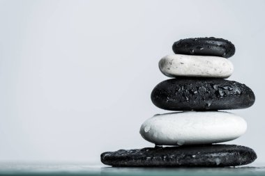 Close up view of water drops on stacked black and white zen stones on wet glass isolated on grey clipart