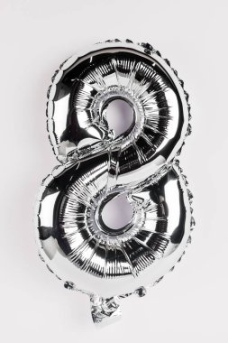 Gri arkaplanda sekiz numara şeklinde gümüş bir balon.