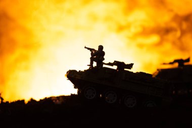 Silhouette of toy soldier on tank with fire at background, battle scene clipart