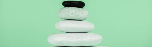 Panoramic shot of stacked zen stones isolated on green 