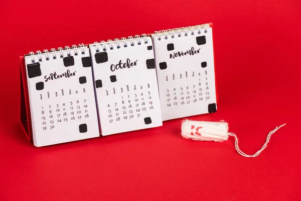 Kalender Und Hygienetampon Mit Traurigem Gesichtsausdruck Auf Rotem Hintergrund — Stockfoto