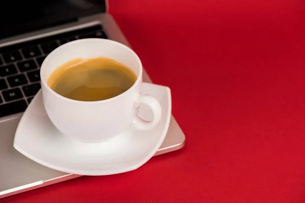 Kırmızı Yüzeydeki Dizüstü Bilgisayardaki Kahve Fincanını Kapat — Stok fotoğraf