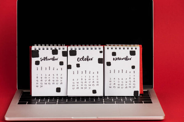 Calendar with autumn months on laptop with blank screen on red background