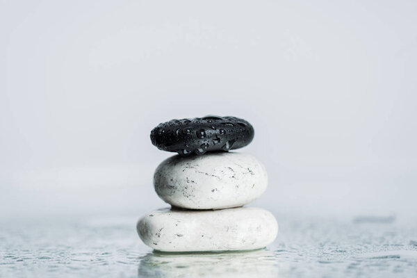 Wet zen stones on glass with water drops isolated on grey 