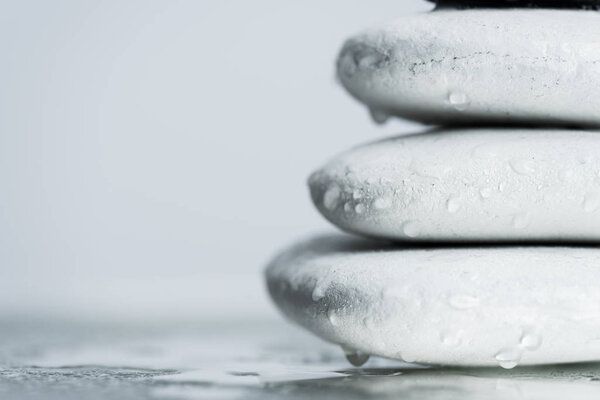 Macro shot of white zen stones in water drops on wet glass isolated on grey