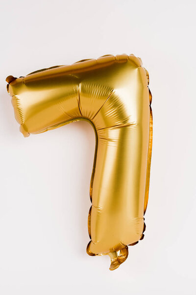 Golden balloon in shape of seven number on grey background
