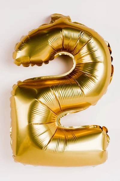 Golden balloon in shape of two number on grey background