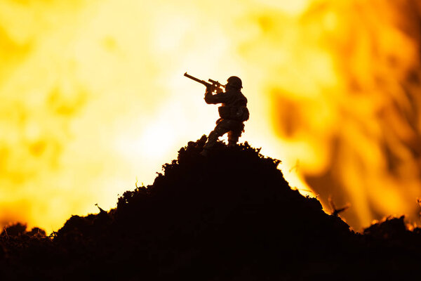 Battle scene with toy warrior on battleground and fire at background