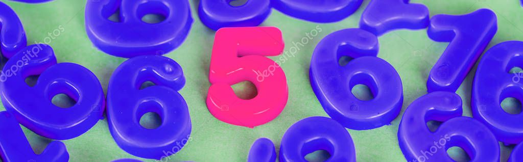 Panoramic shot of pink five number and blue numbers on green surface
