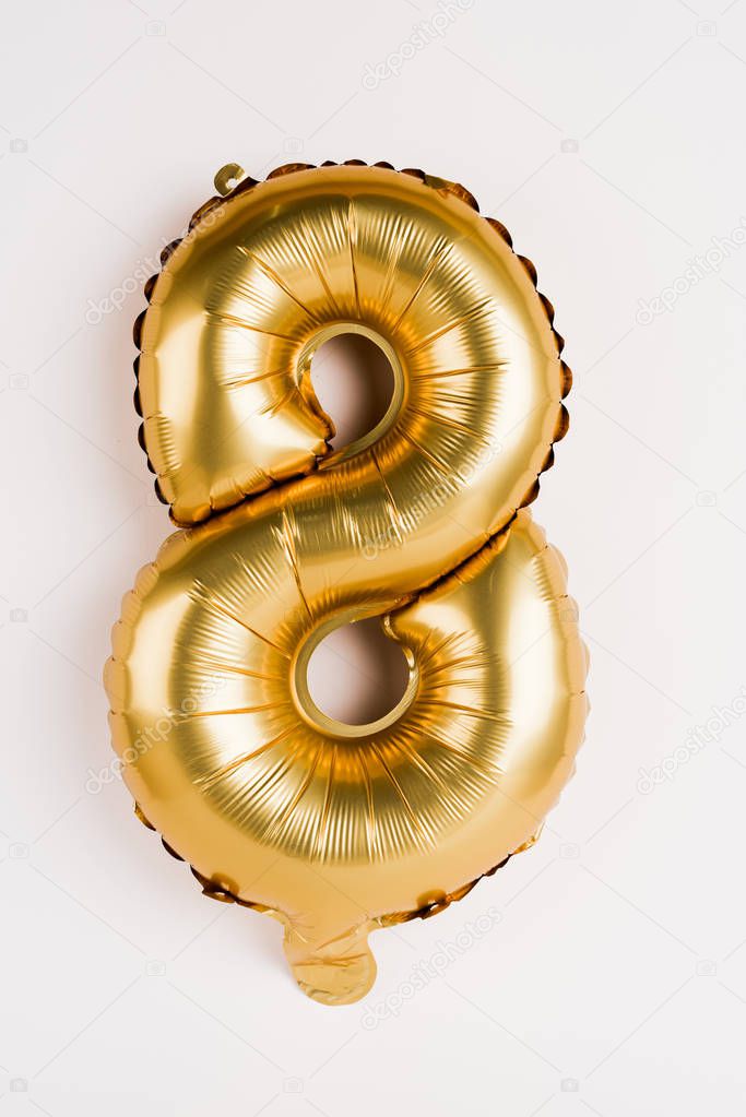 Decorative golden balloon in shape of eight on grey background