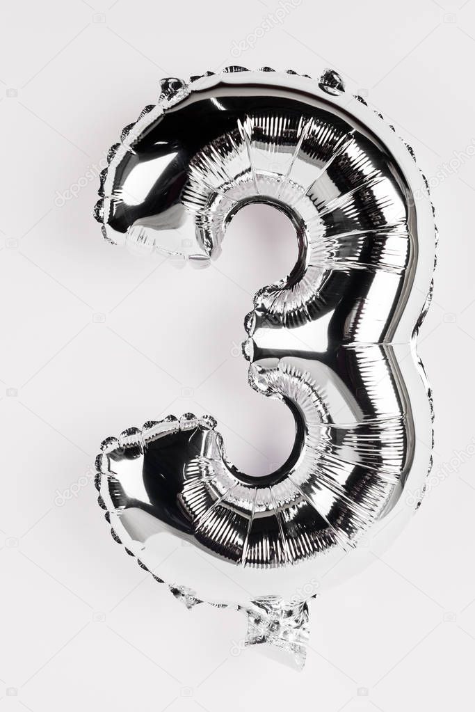 Silver balloon in shape of three number on grey background