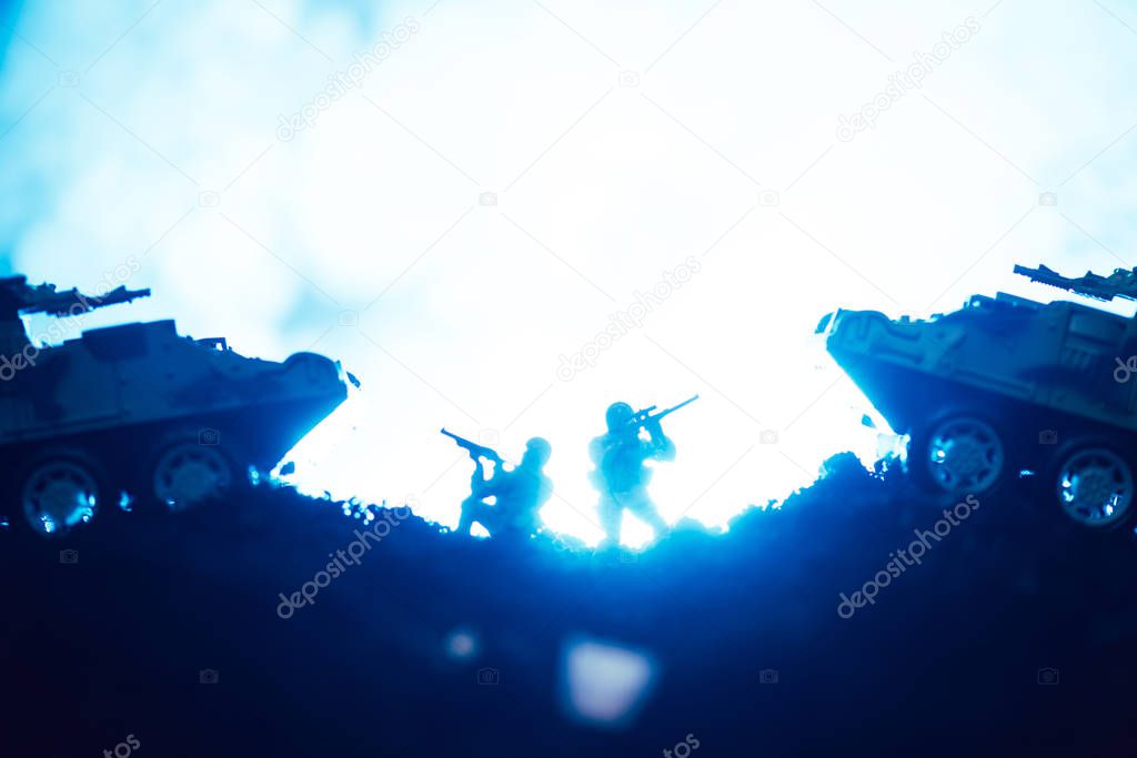 Battle scene of toy warriors and tanks with smoke on blue background