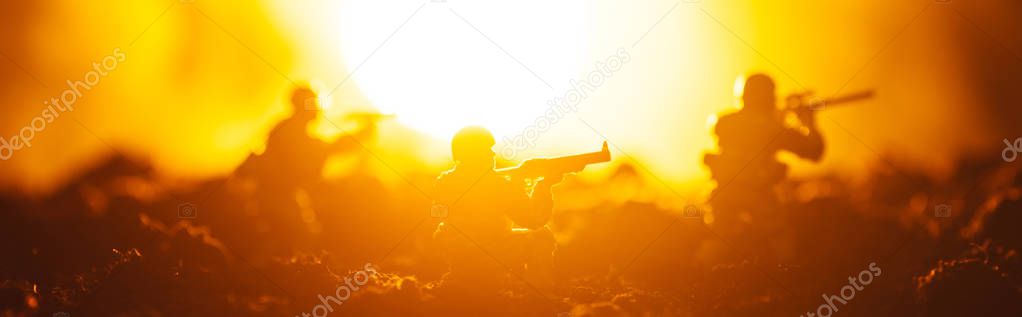 Battle scene of toy soldiers with sun on orange background, panoramic shot