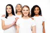 happy multicultural women in white t-shirts looking at camera isolated on white 