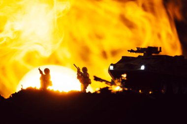 Scene of battle with toy warriors, tank and smoke with sunset at background clipart