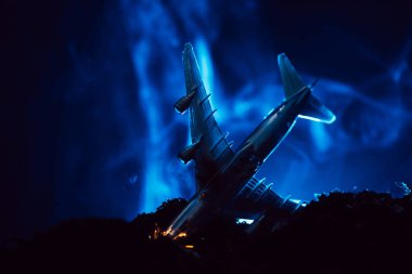 Siyah arka planda mavi dumanlı oyuncak uçak kazası sahnesi