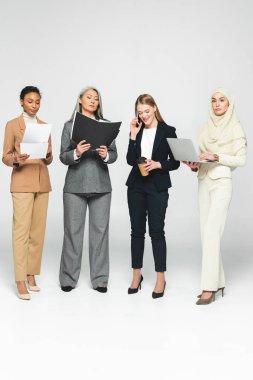 Dosyaları olan çok kültürlü iş kadınları akıllı telefonlardan beyaz kadınlara konuşuyorlar. 