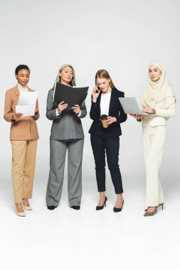Dosyaları olan çok kültürlü, çekici iş kadınları akıllı telefonlardan beyaz kadınlara konuşuyorlar. 