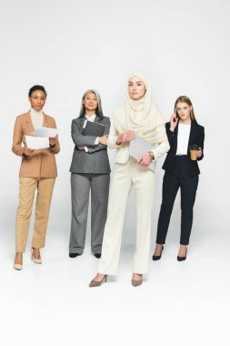 Beyaz dizüstü bilgisayarı olan Arap bir kadının yanında çok kültürlü iş kadınları. 