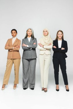 Güzel, çok kültürlü kadınlar kollarını beyaza kavuşturmuş duruyor. 