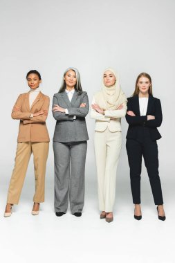 beautiful multicultural women standing with crossed arms on white  clipart