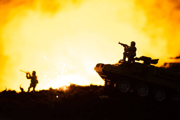 Toy soldiers, tanks and explosion on battleground with fire at background