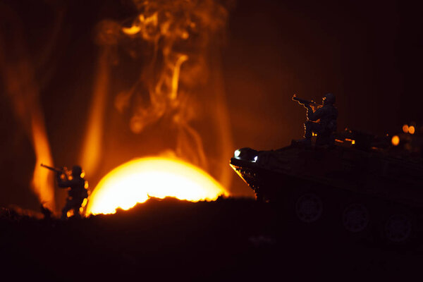 Battle scene with toy warriors and tank in smoke with sunset at background