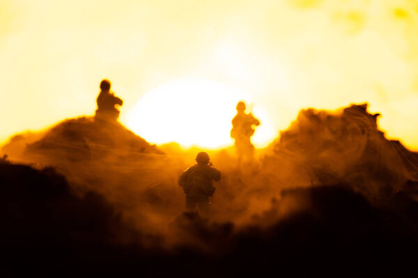 Селективный фокус игрушечных воинов на поле боя с закатом на заднем плане, сцена боя
