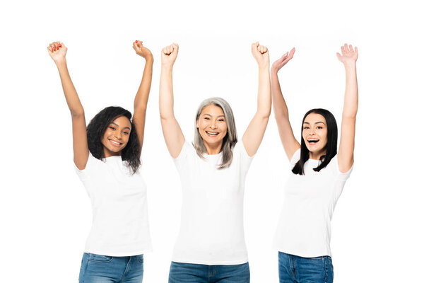 cheerful multicultural women with hands above head celebrating isolated on white 