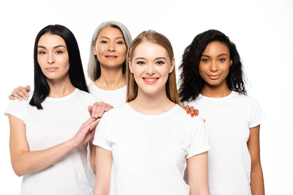 happy multicultural women in white t-shirts looking at camera isolated on white 