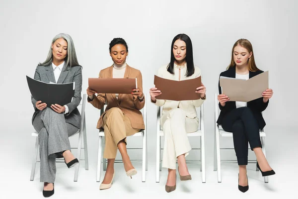 Four Multicultural Businesswomen Suits Sitting Chairs Looking Folders White — Stock Photo, Image
