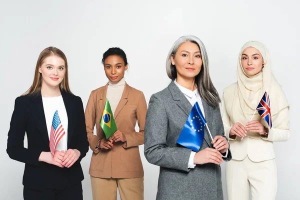 Farklı ülkelerden bayrakları olan çok kültürlü iş kadınları beyazlar üzerinde izole edilmiş 