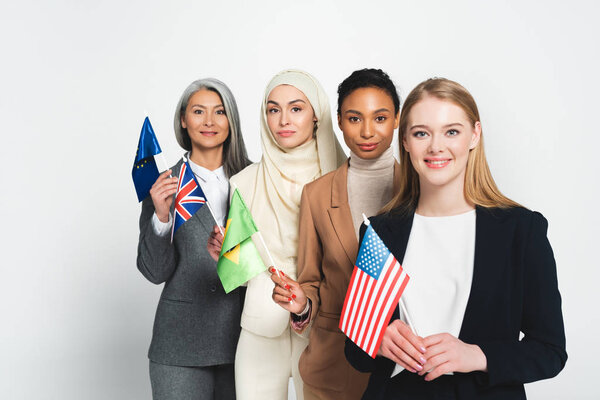 attractive multicultural businesswomen with flags of different countries isolated on white 