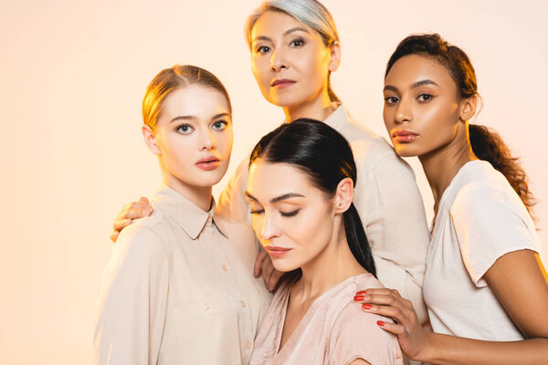 four attractive multicultural women with makeup isolated on beige 