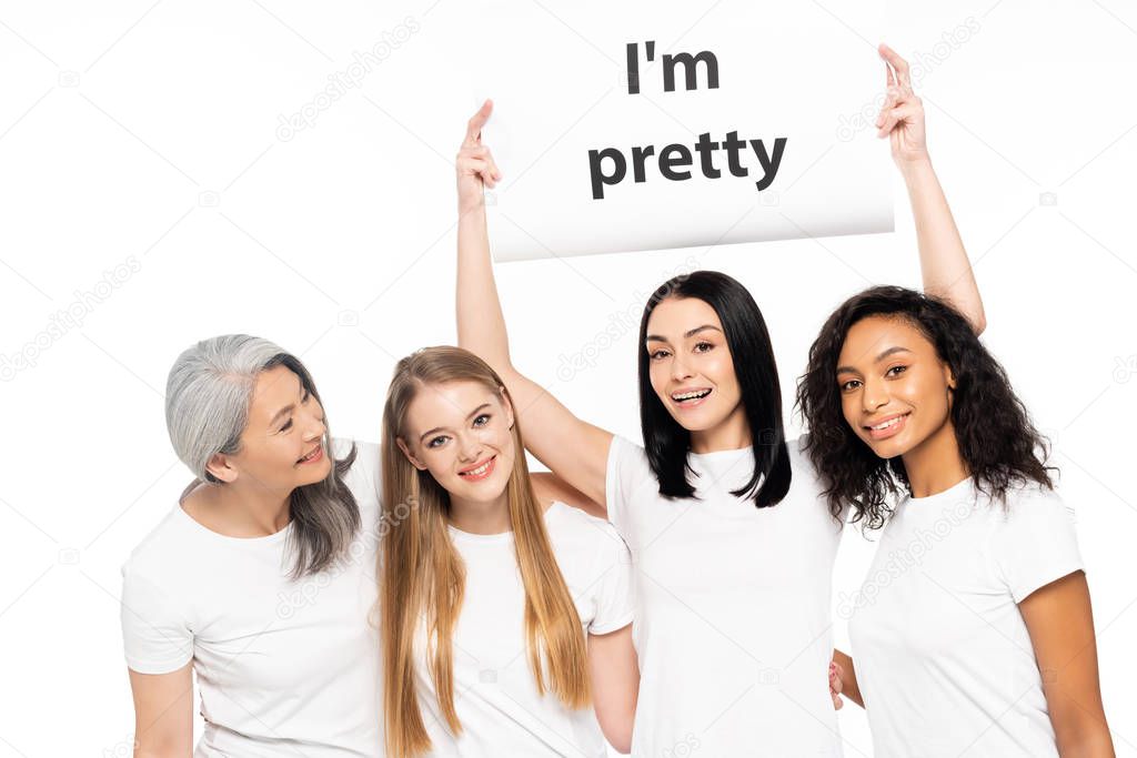 happy multicultural women near placard with i`m pretty lettering isolated on white 