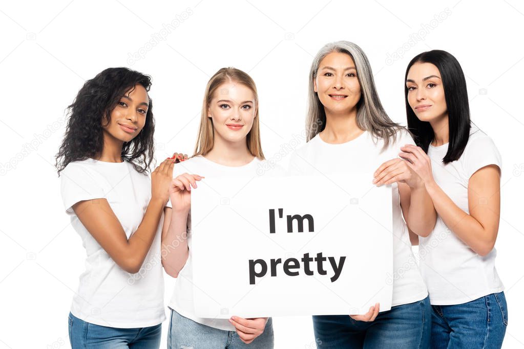 cheerful multicultural women near placard with i`m pretty lettering isolated on white 