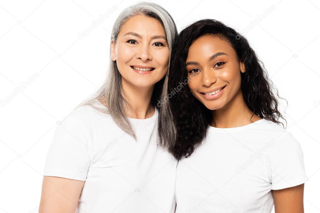 happy african american and asian women looking at camera and smiling isolated on white 