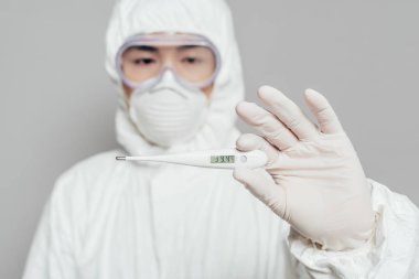 Asyalı epidemiyologların seçici odak noktası termometreyi gösteriyor ki yüksek sıcaklık gri, panoramik çekimde izole edilmiş.