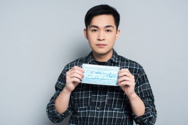  young man showing respirator mask with 2019-ncov lettering on grey background