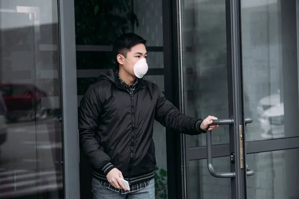 Pria Asia Muda Bertopeng Respirator Memegang Smartphone Dan Berpaling Sambil — Stok Foto