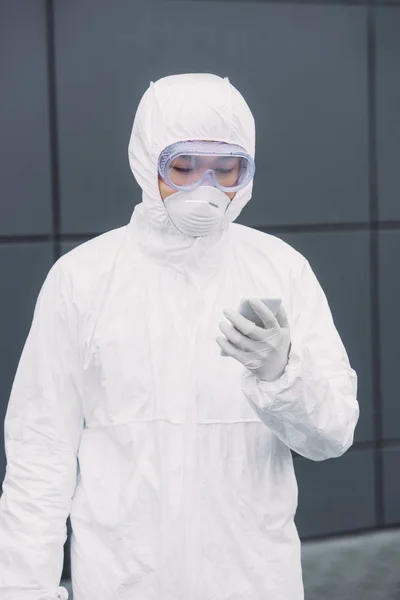 Asian Epidemiologist Hazmat Suit Respirator Mask Standing Looking Smartphone — ストック写真