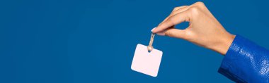 cropped view of african american woman holding blank label isolated on blue, panoramic shot