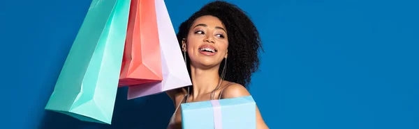 Щаслива Красива Афроамериканка Тримає Подарункову Коробку Сумки Дивлячись Синій Фон — стокове фото